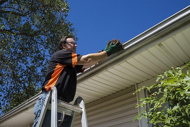 repairman using a ladder to access a damaged gutter for repair in Boca Raton